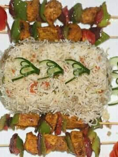 A picture of Egg fried rice with chicken shahlik sticks.