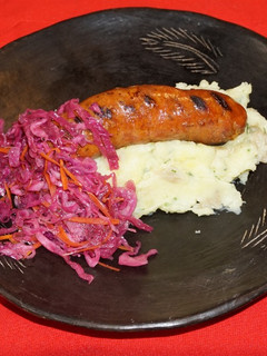 Una foto de Longaniza sureña casera con puré de papas al ajillo y chucrut morado