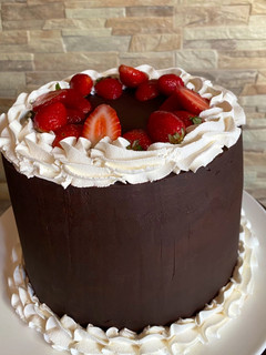 Una foto de Torta de chocolate con crema, frutillas y ganache