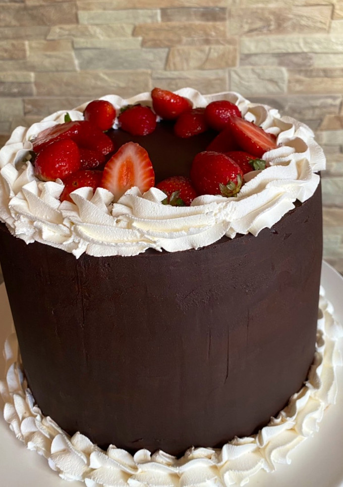 Una foto de Torta de chocolate con crema, frutillas y ganache