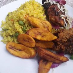 A picture of Fried rice with fried plantain and chicken.