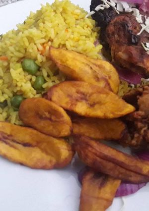 A picture of Fried rice with fried plantain and chicken.