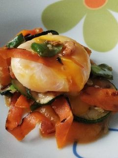 Una foto de Yema de huevo poché sobre puré de calabaza, verduritas y gambas