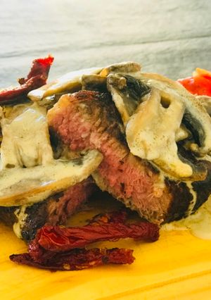 Una foto de Bife de chorizo con salsa de champiñones, huevo y ensalada cocida de pimiento cebolla y tomate