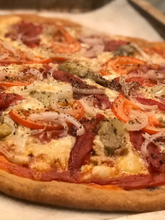Una foto de Pizza con masa de aceituna negra y tomate seco con un toque ahumado