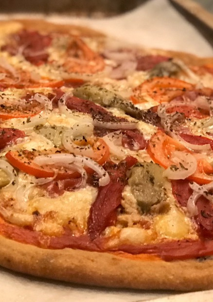 Una foto de Pizza con masa de aceituna negra y tomate seco con un toque ahumado