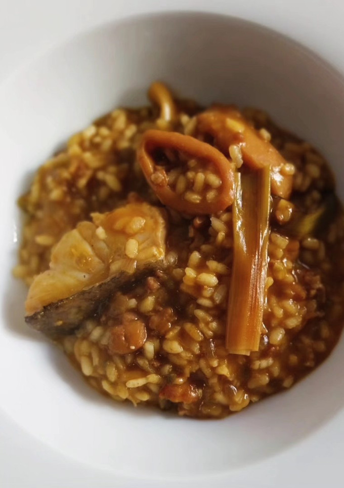 Una foto de Arroz meloso de bacalao, calamar, ajos tiernos y alcachofas