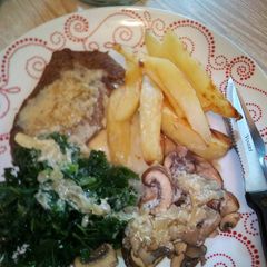 A picture of Light fried steak with peppercorn sauce kale, mushrooms and chip.