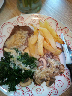 A picture of Light fried steak with peppercorn sauce kale, mushrooms and chip.