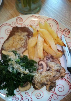 A picture of Light fried steak with peppercorn sauce kale, mushrooms and chip.