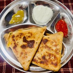 A picture of Aloo Paratha with Curd.