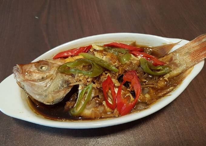 Ikan nila kukus dengan taburan bawang putih dan jahe, disajikan hangat dengan aroma yang menggoda