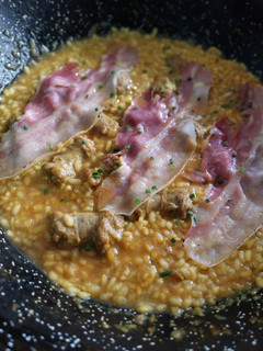 Una foto de Arroz meloso de butifarras con panceta curada a la pimienta