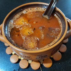 A picture of Tomato soup with fried bread crumbs.