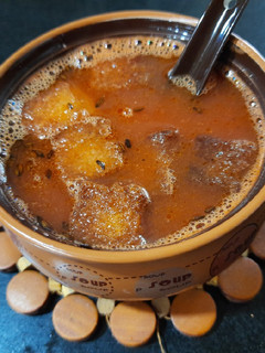A picture of Tomato soup with fried bread crumbs.