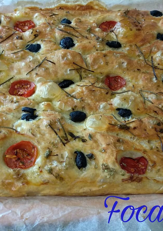 Una foto de Focaccia con aceitunas negras, tomates cherry, romero y orégano
