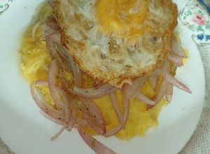 Una foto de Mangú de plátano maduro con huevo y cebolla