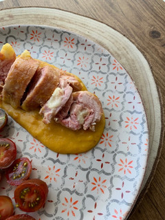Una foto de Enrollado de pollo relleno de jamón y queso con salsa de verduras