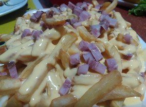 Una foto de Papas fritas con salsa cheddar y panceta