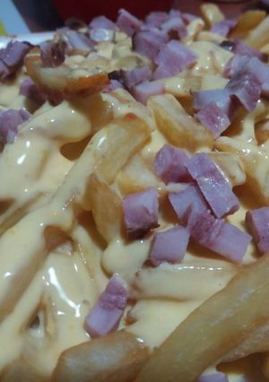 Una foto de Papas fritas con salsa cheddar y panceta