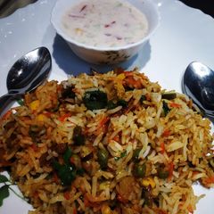 A picture of Vegetable Dum Biryani with Onion,Tomato and cucumber Raita.