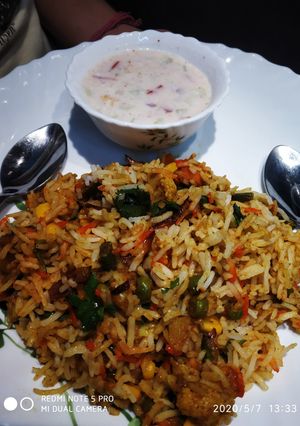 A picture of Vegetable Dum Biryani with Onion,Tomato and cucumber Raita.