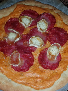 Una foto de Pizza de queso crema, tomate y salami