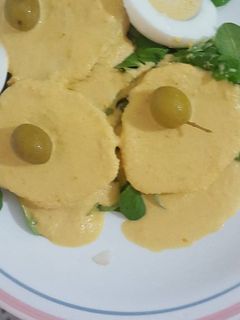 Una foto de Papa la huancaína acompañado con canónigos y rúcula