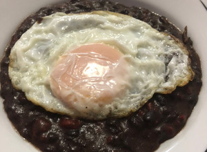 Una foto de Frijoles con chorizo, con huevo estrellado encima