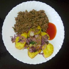 A picture of Roast Potatoes garnished with onions and coriander served with minced meat.