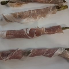 A picture of Asparagus wrapped in prosciutto ham.