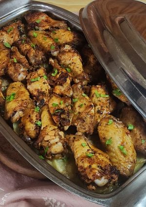 Una foto de 🍗🥔🧅 Alitas de pollo al horno sobre colchón de papas y cebollas 🧅🥔🍗