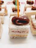 Canapés de paté de salmón ahumado, queso y jamón serrano coronados con anchoa