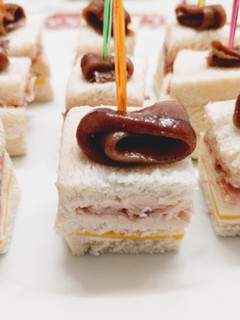 Una foto de Canapés de paté de salmón ahumado, queso y jamón serrano coronados con anchoa