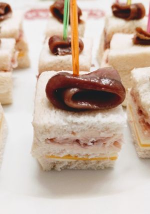 Una foto de Canapés de paté de salmón ahumado, queso y jamón serrano coronados con anchoa