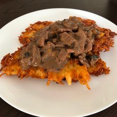 Beef goulash with mushrooms served on potato pancakes A picture of Beef goulash with mushrooms served on potato pancakes.