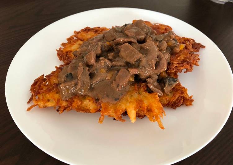 Beef goulash with mushrooms served on potato pancakes