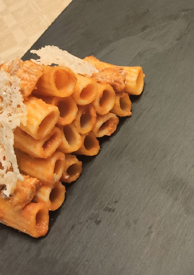 Una foto de Rigatoni con tomate y teja de queso parmesano
