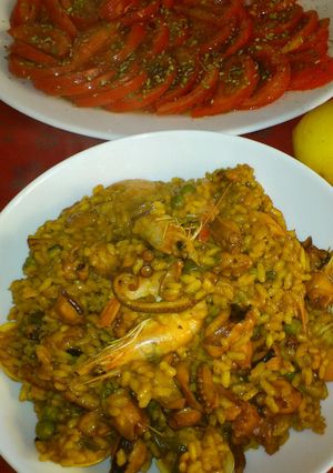 Una foto de Arroz con pulpo, langostinos y almejas, acompañado de picada de tomates aliñados