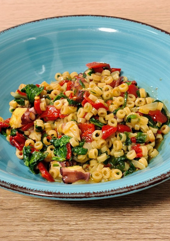 Una foto de Pasta corta con pulpo, espinacas y piquillo
