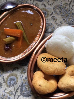 A picture of Andhra style Uddina vada and Idli served with sambhar.