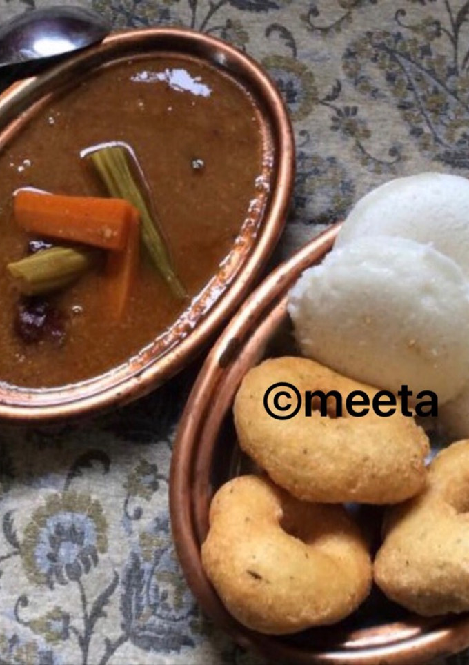A picture of Andhra style Uddina vada and Idli served with sambhar.