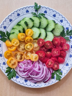 Una foto de Ensalada multicolor de tomates cherry rojos y amarillos con cebolla morada y pepino ❤️💛💜💚
