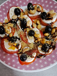 Una foto de Ruleta de tomates con queso fresco, frutos secos, aceitunas y orégano