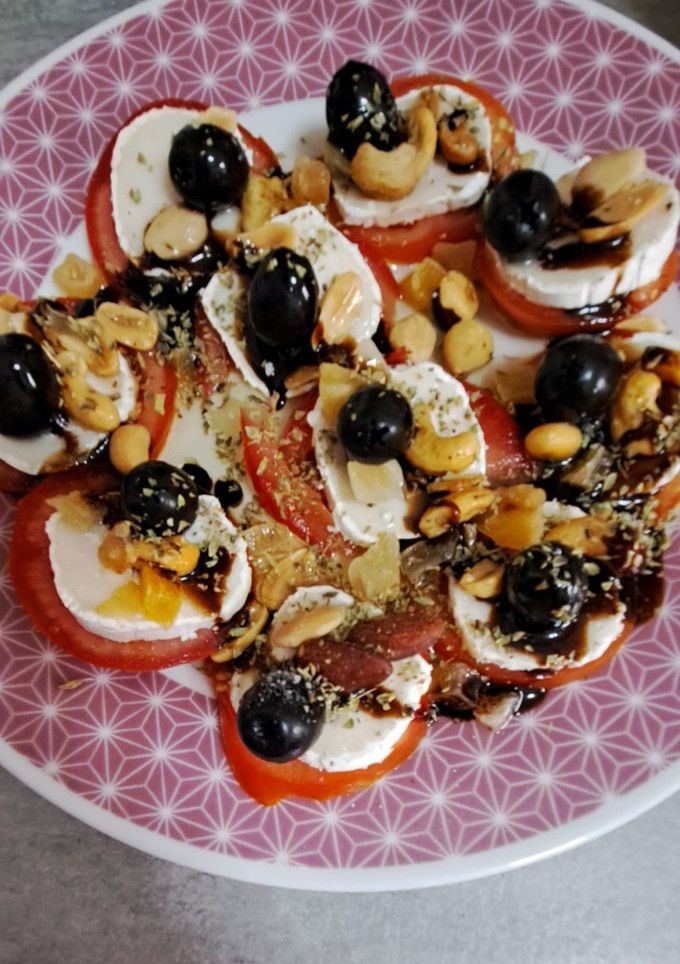 Una foto de Ruleta de tomates con queso fresco, frutos secos, aceitunas y orégano