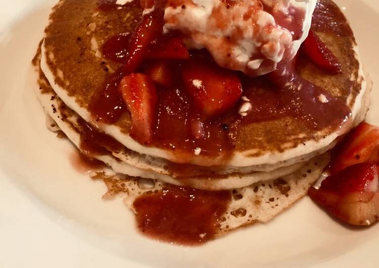 Pancakes loaded with whipped cream and strawberries