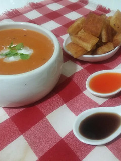 A picture of Tomato carrot soup with croutons.