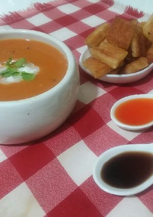 A picture of Tomato carrot soup with croutons.