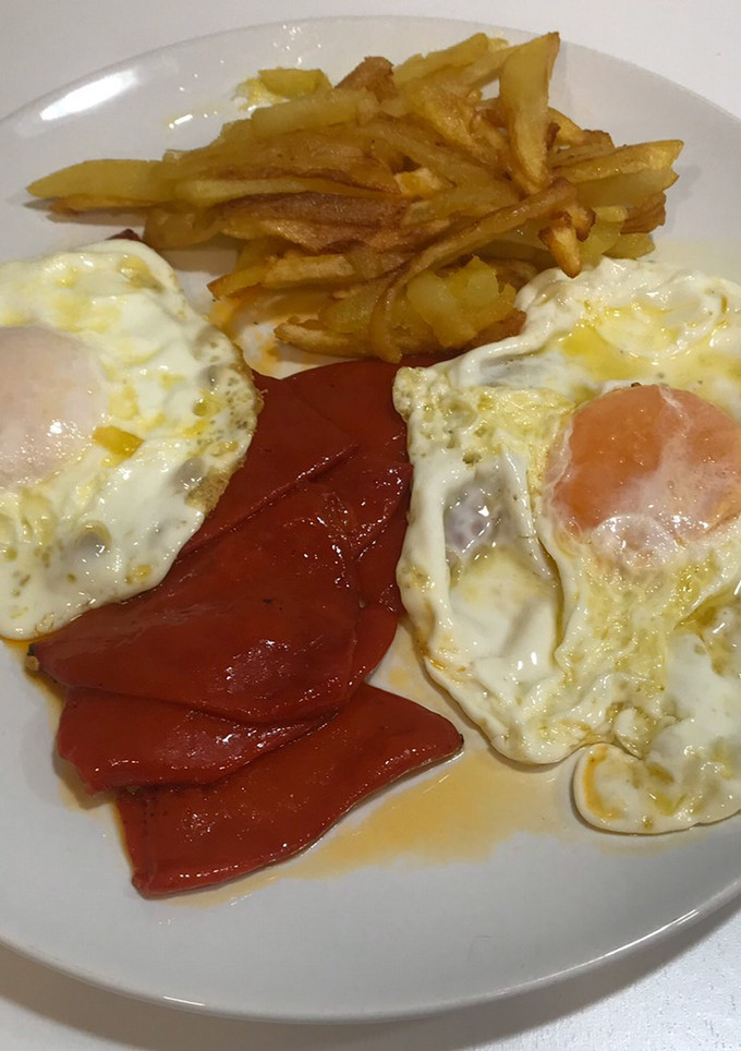 Una foto de Huevos fritos con pimientos del piquillo y patatas fritas