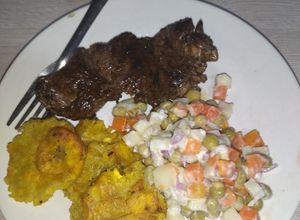 Una foto de Carne de res al vino tinto, acompañado de patacones y ensalada